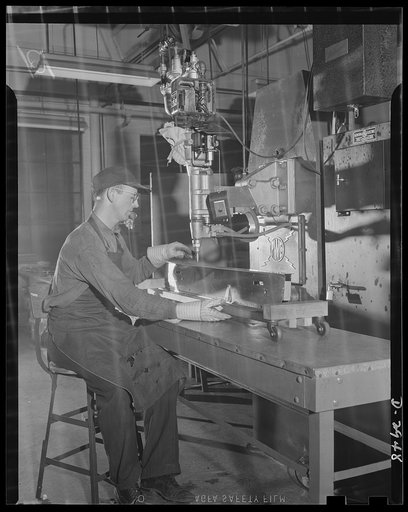 Conversion. Silverware plant. Undergoing conversion to production of bomb shackles from silver tableware, employees of an Eastern plant are helping America deal death to the Axis. Worker operating the progressive welder is fabricating bomb shackle frames. More than 500 operations on 100 parts are re