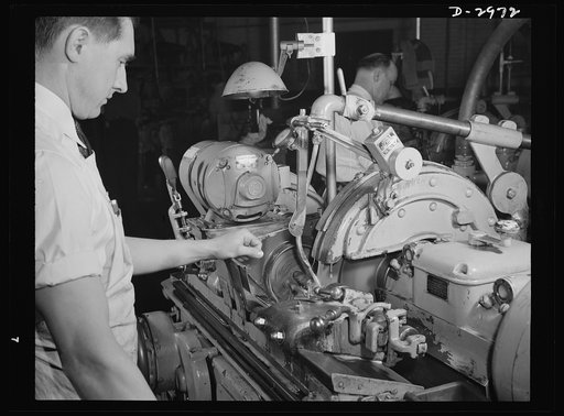 Conversion. Electric shaver plant. Normal peacetime work of this New England plant is the production of electric dry shavers. The worker on this Norton type C six-inch semi-automatic cylindrical grinder normally grinds the rotor shaft for the motor of the shaver using this set-up. He has since been 