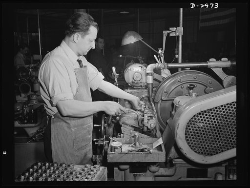 Conversion. Electric shaver plant. This worker in a New England plant that normally produces electric dry shavers is now busy turning out spring collets for machine tools to be used in war production. On this Norton type C six-inch semi-automatic cylindrical grinder, he used to turn out rotor shafts