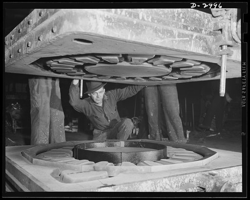 Aluminum casting. It's a delicate operation, this closing of the cope on a large sand mold. When the parts are locked together, the molten aluminum is poured into the mold. Aluminum Industries Inc., Cincinnati, Ohio
