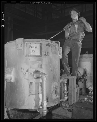 Aluminum casting. It takes skill and dexterity to perform this operation. A worker in an aluminum foundry puddling and skimming a 450-pound crucible tilting furnace. Aluminum Industries Inc., Cincinnati, Ohio