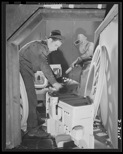 Aluminum casting. These castings have been sandblasted to clean them and remove all excess material. Two workmen of a large Midwest aluminum factory here remove the finished sandblasted castings from the turntable. Aluminum Industries Inc., Cincinnati, Ohio