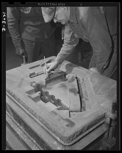 Aluminum casting. Brushing and inserting cores into the assembled mold, one of the many delicate operations required of skilled workmen in a large Midwest factory. Aluminum Industries Inc., Cincinnati, Ohio