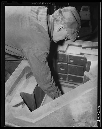 Aluminum casting. Molds must be touched up before cores can be placed in them; another step in the delicate technical process of casting for aluminum products. Aluminum Industries Inc., Cincinnati, Ohio