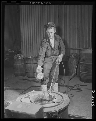 Aluminum casting. A new development in the production of war materials involves use of magnesium. Here a young worker in a large Midwest foundry takes temperature readings of molten magnesium alloy through the protective crust. At the same time he is sprinkling flux to prevent burning at the hole in