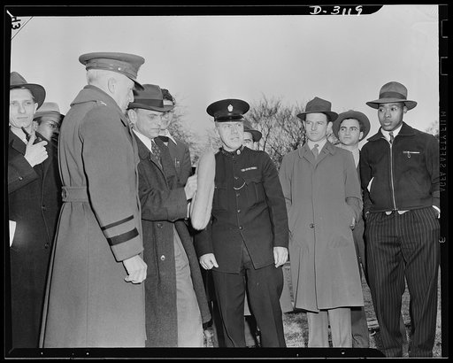 Constable Scott of London (right) with Director Landis of Office of Civilian Defense (center) and Major General L. D. Gasser, Head of Protection Division, Office of Civilian Defense (left). Dean Landis holds a sandbag with hand grip used to extinguish incendiary bombs. This type of bag also serves a
