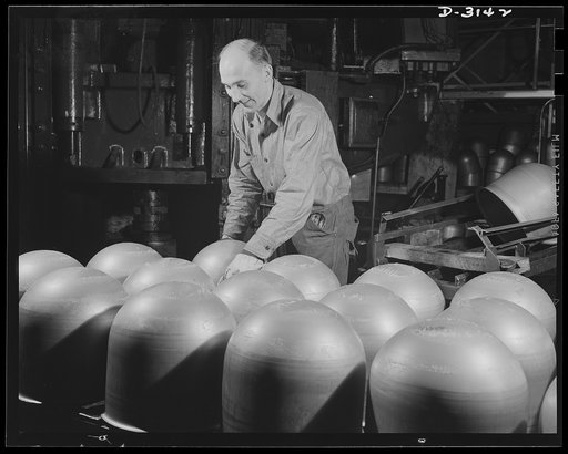 Conversion. Beverage containers to aviation oxygen cylinders. After they are stamped on the huge toggle press in the metal division of a large rubber factory, these cylindrical domes which make up half of a shatterproof oxygen cylinder, are placed on a large conveyor where they are carried to workme