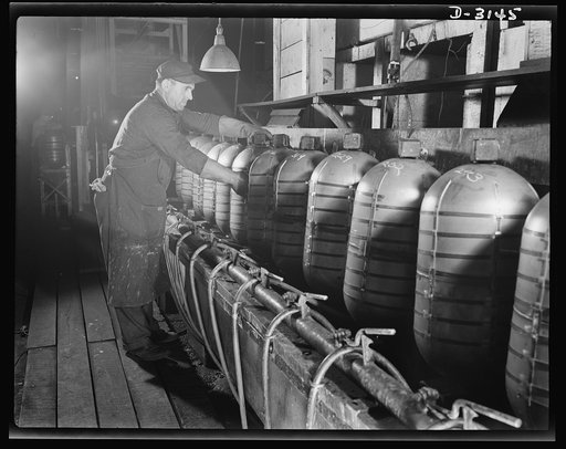 Conversion. Beverage containers to aviation oxygen cylinders. Once the two-half cylinders are joined together into a complete shatterproof high altitude flying oxygen cylinder on the production line of a huge rubber factory now producing metal essential for the Army, all traces of inside weld scale 