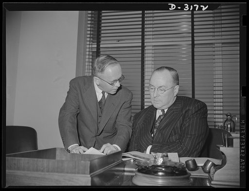 Donald Nelson, Chairman of the War Production Board, studies the program by which America's farm women plan to help win the war. Graham Patterson, publisher of Farm journal and farmer's wife, national farm magazine, is seen here presenting the "War Platform" which twenty-eight leading farm women, sp