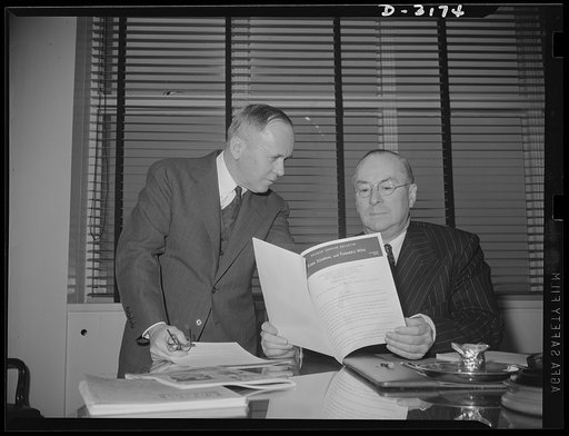 Donald Nelson, Chairman of the War Production Board, studies the program by which America's farm women plan to help win the war. Graham Patterson, publisher of Farm journal and farmer's wife, national farm magazine, is seen here presenting the "War Platform" which twenty-eight leading farm women, sp