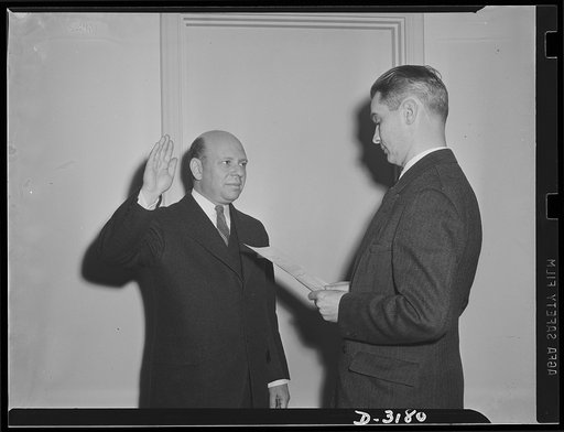 Administering oath. Herbert Emmerich, former Secretary of War Production Board, now Administrator of Defense housing Authority and J.C. Hale, of Bureau of Budget, Assistant Administrator Officer, administering the oath
