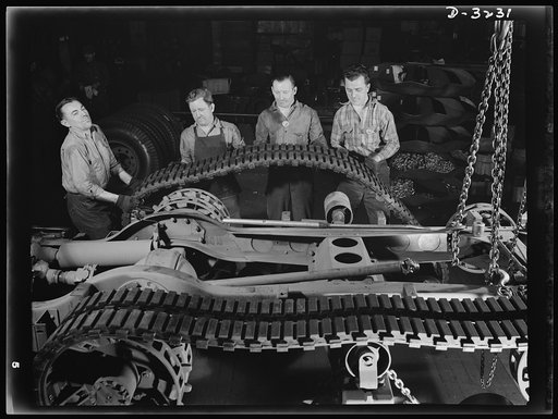 The fine maneuvering qualities of the Army's halftrac scout car depends largely on the tractor belt. The mounting of the belt on the chassis is handled deftly by a skilled crew on the assembly line of an Ohio truck manufacturer. White Motor Company, Cleveland, Ohio