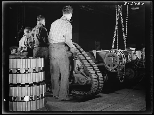 The fine maneuvering qualities of the Army's halftrac scout car depends largely on the tractor belt. The mounting of the belt on the chassis is handled deftly by a skilled crew on the assembly line of an Ohio truck manufacturer. White Motor Company, Cleveland, Ohio