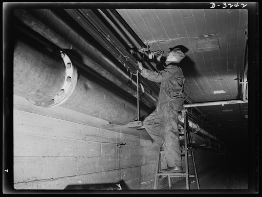 "Bog-downs" and bottlenecks in defense plant operation are out for the duration. Maintenance crews are eternally at it to keep everything in good working order. Inspecting electrical wiring in a tunnel between two buildings is only one of innumerable items in the continuous maintenance program of a 