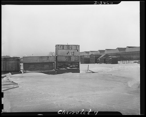 Auto conversion to airplane engines. Some of the equipment impossible to convert from automobile engine manufacture to production of airplane motors is shown back of a huge automobile factory. A dismantled paint booth (left foreground) is among the scrap. In the background, against the rising glass 