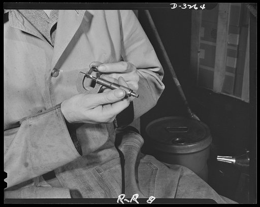 Oil burners to machine gun parts. Using a micrometer to check this small part for an army machine gun, this worker must achieve tolerance not greater than 1/10,000 of an inch. This upper New York state factory, which formerly produced oil burners, is under contract for 75,000 small precision parts f