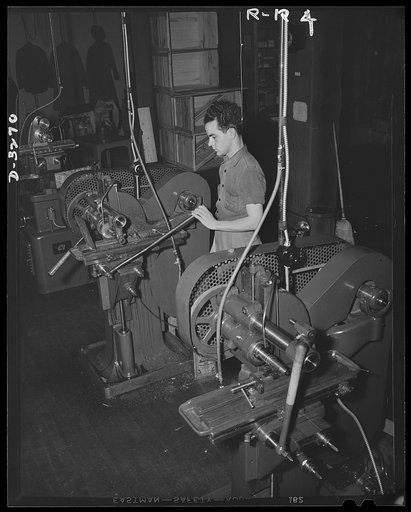 Oil burners to machine gun parts. With conversion of a New York State oil-burner plant to production of precision parts for machine guns, additional equipment and manpower were mandatory. Unable to purchase sufficient new machines, these two used to hand operated milling machines were installed. The