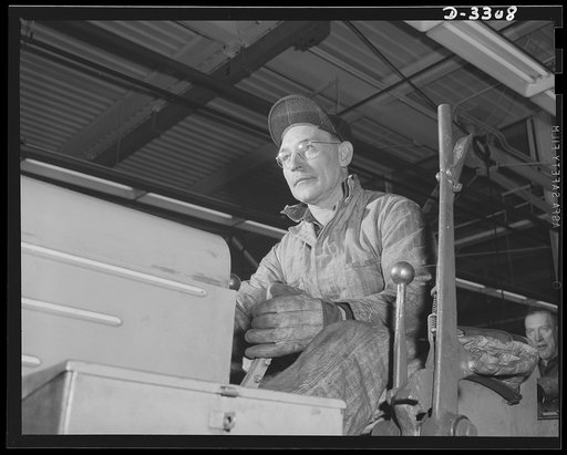 In a big automobile plant changing over to production of shells, this "Cat Skinner" (tractor operator) was kept busy for some time pulling, turning and bulldozing machines into new location. Oldsmobile, Lansing, Michigan