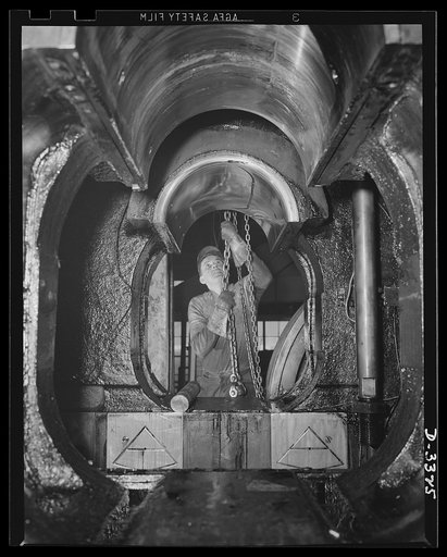 A huge forge hammer in an automobile plant is converted to war work. The importance of the auto in American life is proving to be tremendous advantage as the the great automotive plants pool their resources in the mightiest war production effort the world has ever seen. Oldsmobile, Lansing, Michigan