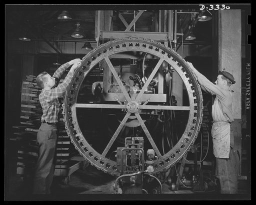 The tracks for an Army halftrac scout car begins to take shape on the "building wheel" of a Midwest tire plant. Goodrich, Akron, Ohio