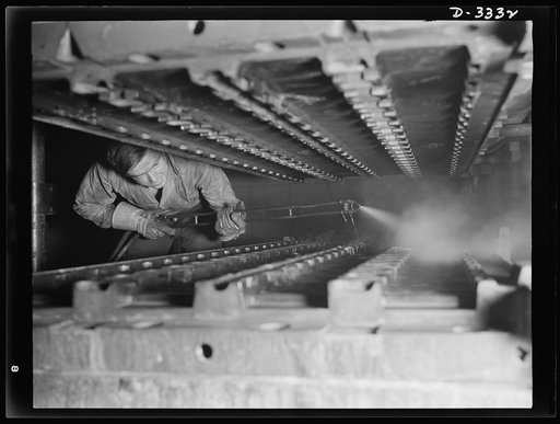 Tracks for Army halftracs cars, made of rubber firmly bonded to steel members, are cured under heat and pressure in tracks molds which are first sprayed with a mold lubricant. The work is done in an Ohio tire plant. Goodrich, Akron, Ohio