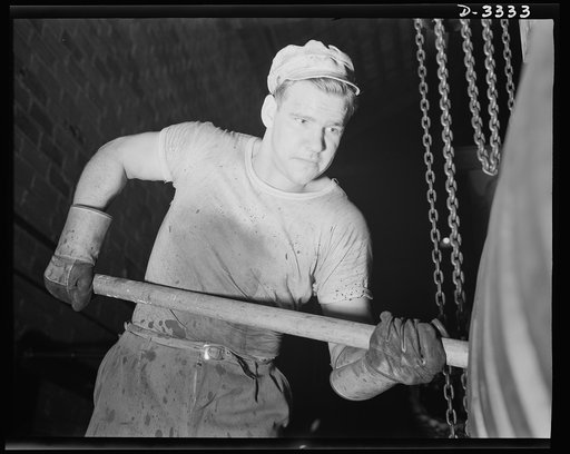Halftrac production. The track of an Army halftrac is positioned in the curing mold at a Midwest rubber plant. The operation is performed with a wooden paddle. Goodrich, Akron, Ohio