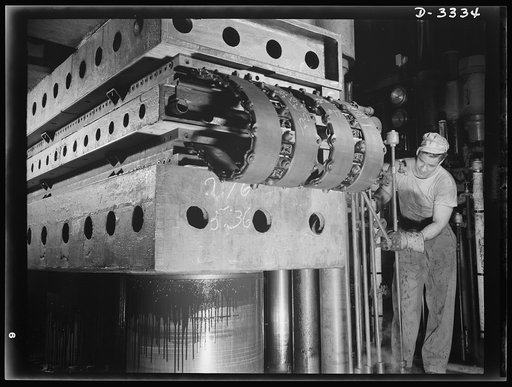 Tracks for scout cars and other Army vehicles go through a curing process in an Ohio tire plant. The hydraulic press in which this important operation is performed assures uniform cure under automatically regulated temperature. Goodrich, Akron, Ohio