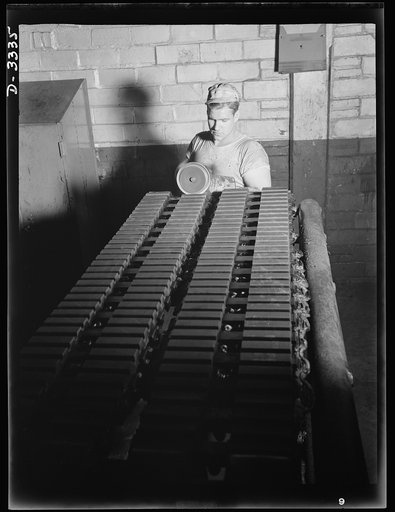 Tracks for Army vehicles, fresh from the curing press of a large Ohio tire plant. Grooves are buffed on the ends of the track section. Goodrich, Akron, Ohio