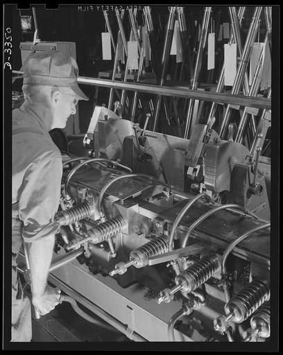 Twenty-millimeter machine guns for planes. A production lathe in a former auto plant and an experienced automobile worker team up to give our air force the greatest possible number of the finest possible machine guns. Oldsmobile, Lansing, Michigan
