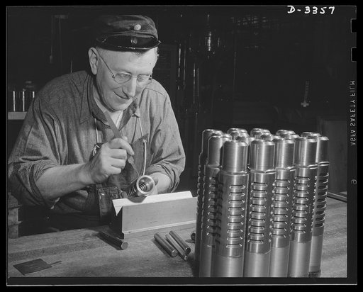 Twenty-millimeter machine guns for planes. The muzzle break of a machine gun for the Air Corps must be right. An inspector in a big auto plant now converted to war work examines each piece as it travels down the production line. Oldsmobile, Lansing, Michigan