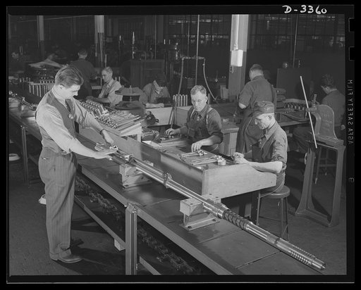 Twenty-millimeter machine guns for planes. An assembly line in a converted auto plant, now turning out machine guns for the Air Corps, comes through with plenty of these important tools of war. And the tide of American productive power is still far from being reached. Oldsmobile, Lansing, Michigan
