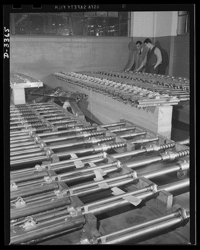 Twenty-millimeter machine guns for planes. American power in the air grows rapidly as machine guns of the finest quality pour from our production lines. These guns, entirely completed and ready to fire, await shipment from the large converted auto plant in which they were made. Oldsmobile, Lansing, 
