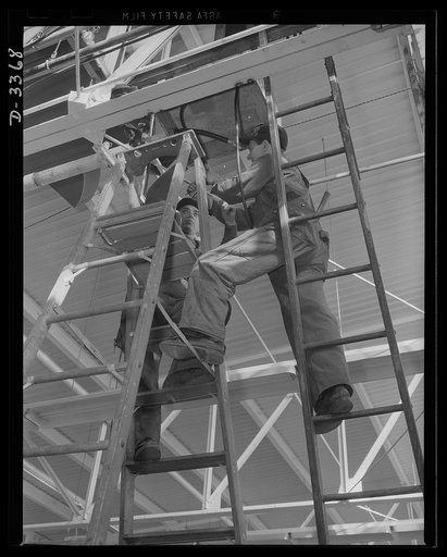 Twenty-millimeter machine guns for planes. A big auto plant changes over to the production of machine guns for the Air Corps. Electricians begin running power lines to the new machine locations. Oldsmobile, Lansing, Michigan