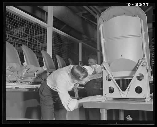 Airplane seat production. Each piece of aluminum necessary to the manufacture of airplane pilot seats must be thoroughly checked before being assembled in this large Midwest rubber factory now converted to war production. Should the precision gauge show up the tiniest imperfection in placement or dr