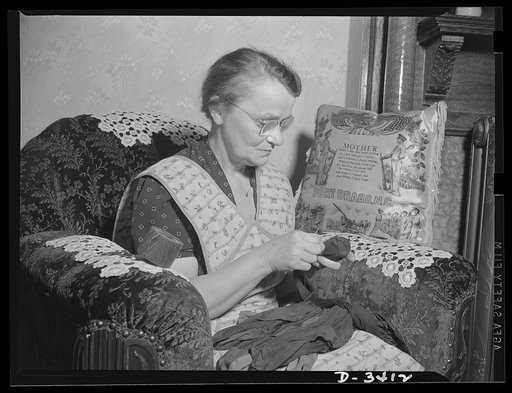 Women at war (Mrs. Smuda). If you didn't know better, you might think Mrs. Smuda spent the day comfortably darning socks for the family. Less than an hour before these pictures were made, this fifty-five-year-old mother and grandmother was skillfully tapering shells for machine guns at the Frankford