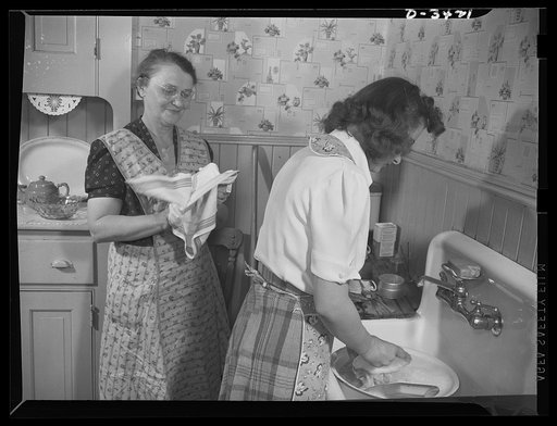 Women at war (Mrs. Smuda). There's a war to be won, but there's work to be done at home, and this modern warrior-mother enjoys taking a hand in household duties. Tonight, she's drying the supper dishes while her daughter Genevieve washes