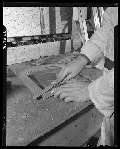 Conversion. Metal screens to bomber windows. Finishing a navigator window frame for a bombing plane in the plant of an Eastern manufacturer of metal door and window screens