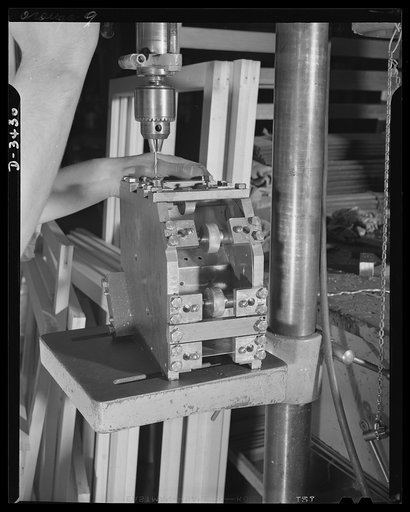 Conversion. Metal screens to bomber windows. An aluminum switch box for an airplane tow target is drilled in a production jig at an Eastern plant that formerly made metal screens for doors and windows