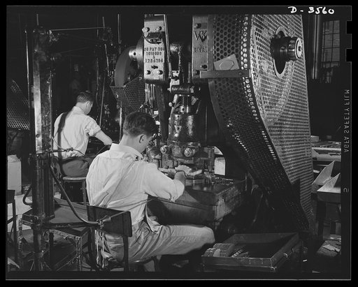 Conversion. Watch cases to war production. Last of the old order. A half-emptied box at a punch press holds the final batch of brass parts for women's compacts to be processed in a Kentucky watch case factory before complete conversion to war prodution. Note safety cords attached to operator's arms.
