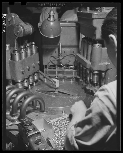 A special automatic machine in a converted cash register factory handles the operations of countercoring, disc inserting, crimping and unloading 20mm fuses. National Cash Register Company, Dayton, Ohio