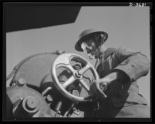 Fort Story coast defense. A job requiring skill and precision: this Fort Story soldier operates the elevation handwheel of a long shore gun. When he receives range specificaton through his earphones, he turns the wheel until the range appears on the gun's range gun