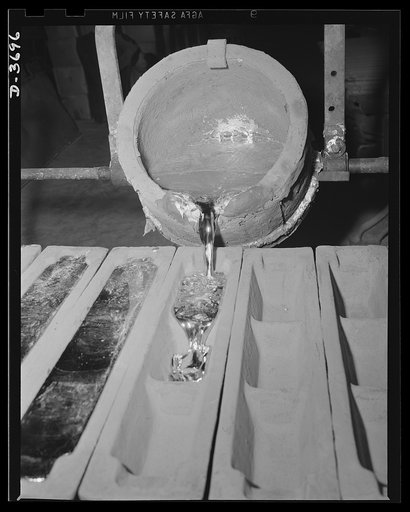 One of the first operations in the production of aluminum parts for America's mechanized army is the discharge of metal from a 300 pound carrying pot into ingot molds. The molten aluminum was first tapped from a furnace into the carrying pot. Aluminum Industries