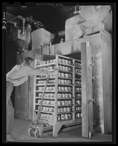 Worker charging heat treating oven for low temperature precipitation treatment of aluminum pistons to be used in U.S. Army jeeps. Aluminum Industries