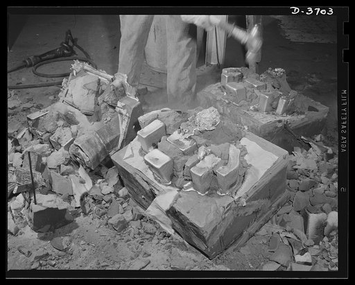 Knocking cores out of molds, another step in the long and intricate process of producing aluminum parts for use by Uncle Sam's mechanized forces. Aluminum Industries