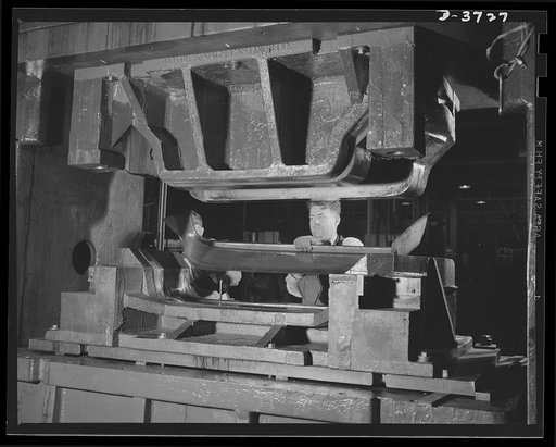 Another blow for Victory. A cowl for an Army jeep is stamped from a flat steel sheet in one of the world's largest automotive plants. The giant 126-ton Bliss double-action press, exerting 350 tons pressure on the sheet, forms a cowl in one operation. Ford Lincoln plant, Michigan