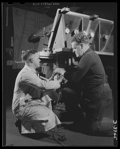 Machine tool experts set up a fixture to be used in drilling tank engine cylinder bores. The no. 4 Cincinnati horizontal mill which will do the work is one of many fine machines in a big automobile factory now being converted to tank production. Ford Lincoln plant, Michigan