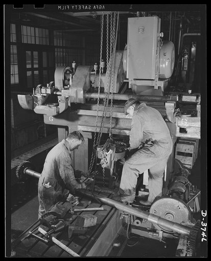 One step in the job of conversion. Machine repair experts of a big automobile plant overhaul and reassemble a planner mill for tank engine production. Ford Lincoln plant, Michigan