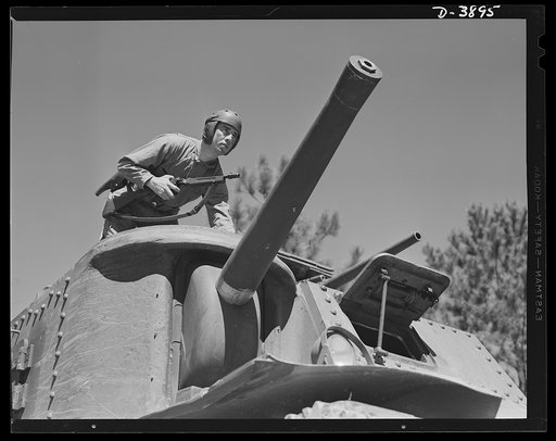 Fort Benning. Tank forces. Double trouble for the Axis -- American manpower and American production ability. The smart soldier ready to alight from a medium (M-3) tank with Tommy gun and side arms is nearing graduation from the armored forces's training school at Fort Benning, Georgia