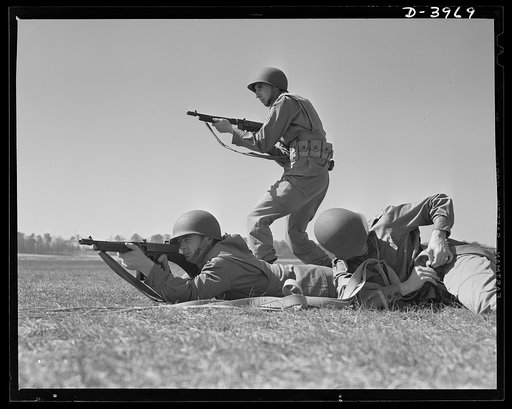 Fort Benning. Tommy gunners, parachute troops. American sky troops. Paratroopers who have just bailed out of planes go into action as soon as they reach the ground. While the last man down is still unbuckling his chute, two comrades go into action with their tommy guns