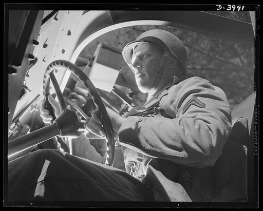 Fort Benning. Halftrac scout cars. Uncle Sam's drivers of the armored forces are the world's best. This corporal, tooling a haflftrac scout car through the training area at Fort Benning, Georgia, will give the Axis many worries
